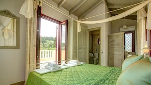 A bedroom with a green quilted bedspread, a balcony with a view, and a wardrobe. - Kalliope Villa - Classic Modern With a Splash of Glam (Paxos)
