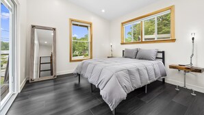 Un dormitorio con cama, ventilador de techo, ventana con vistas y mesita de noche con lámpara.