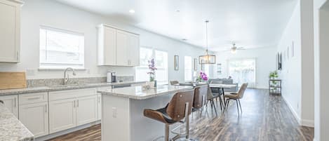 Una cocina amplia con una isla central, taburetes de bar y una zona de comedor con mesa y sillas.