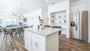 A modern kitchen with white cabinetry, a stainless steel refrigerator, and a granite countertop island. - BRAND NEW CONSTRUCTION NEAR DOWNTOWN & SMF AIRPORT (Sacramento)