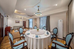 Un salón de conferencias con una mesa redonda, sillas y una lámpara de araña.
