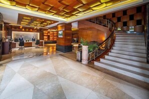 Un vestíbul modern amb una taquilla, una escala i un paviment de marbre.