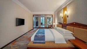 Ein Hotelzimmer mit Bett, Fernseher, einer Sitzecke und Blick ins Freie.