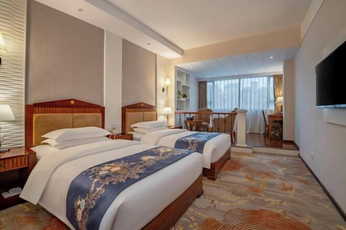 Habitación de hotel con dos camas, un escritorio y un televisor.