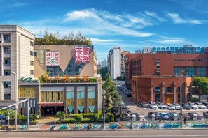 A multi-story building with a prominent sign, a parking lot, and a clear sky. - Kehuayuan Hotel (Chengdu)