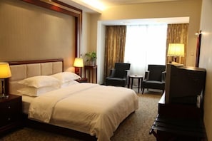 A hotel room with a large bed, two chairs, a small table, and a TV. - Kehuayuan Hotel (Chengdu)