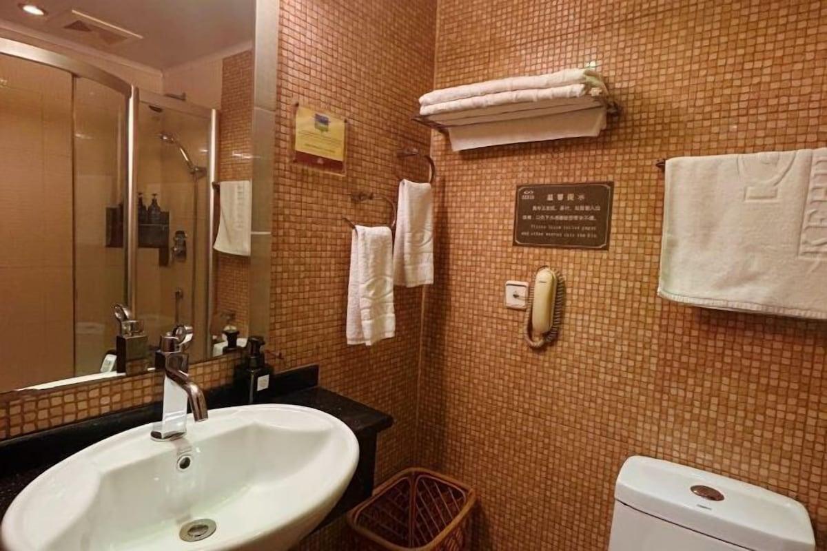 A bathroom with a sink, mirror, towel rack, and a toilet.
