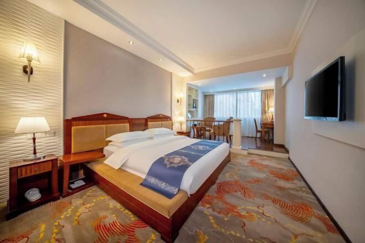 Una habitación de hotel con una cama grande, televisión, escritorio y silla.