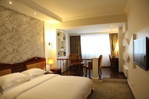A hotel room with a large bed, a desk with a chair, a TV mounted on the wall, and a balcony with a view. - Kehuayuan Hotel (Chengdu)