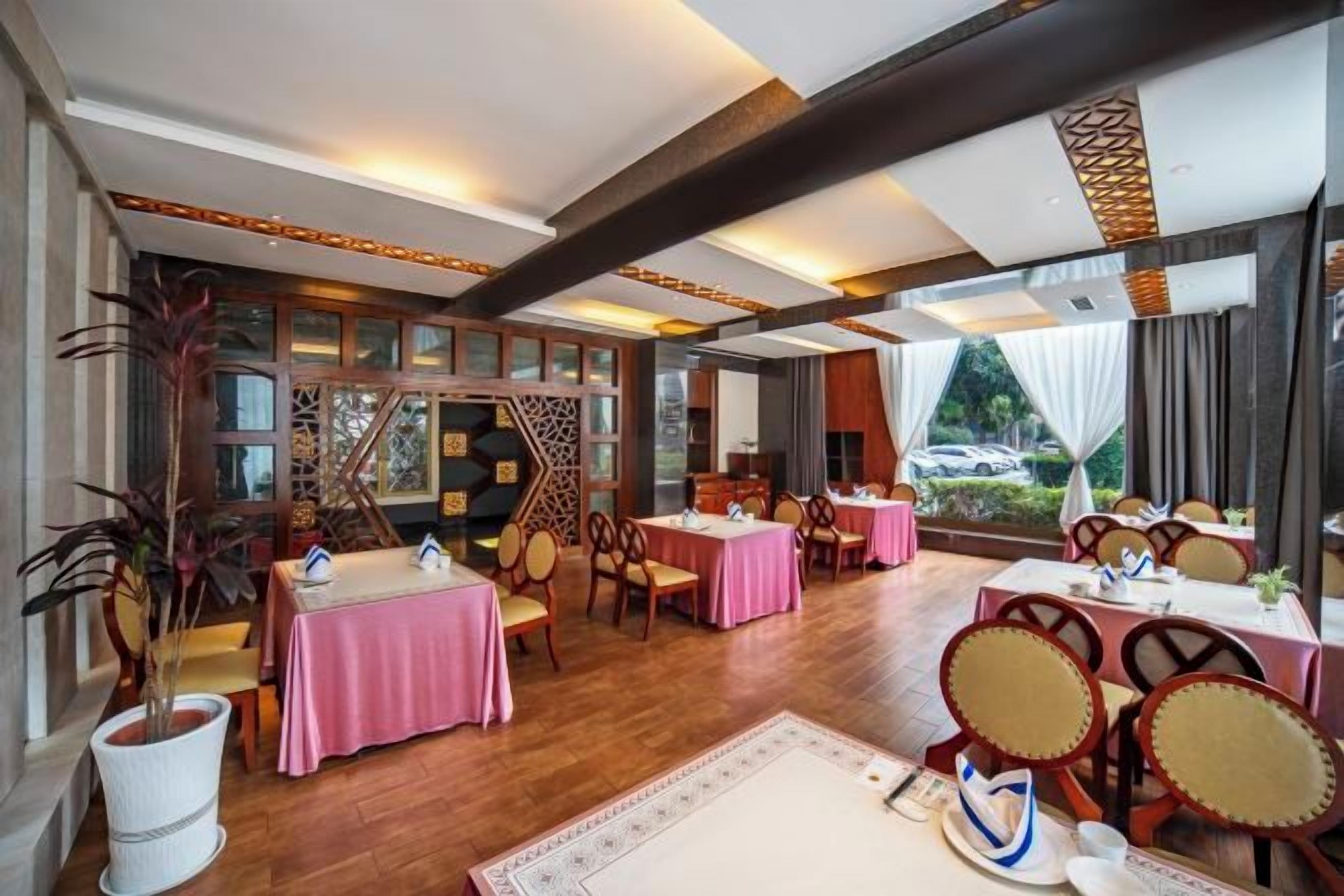 A restaurant with multiple tables and chairs, wooden flooring, and large windows.