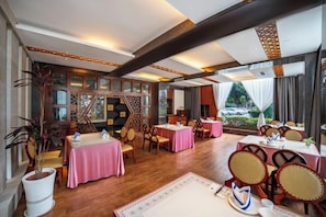 A restaurant with multiple tables and chairs, wooden flooring, and large windows.