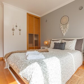 A bedroom with a bed, a wardrobe, a dreamcatcher, and wall decorations.
