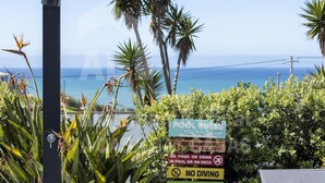 Schild mit Poolregeln und Blick auf den Ozean.