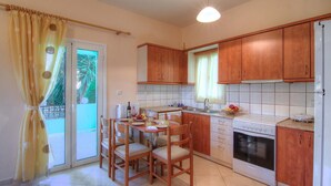 A kitchen with wooden cabinets, a white stove, and a dining table with chairs. - Blue Villa 2 - With Private Pool (Mylopotamos)