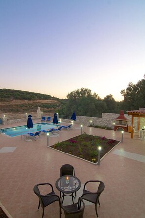 A pool area with lounge chairs and umbrellas, a barbecue area, and a garden with flowers. - Blue Villa 2 - With Private Pool (Mylopotamos)