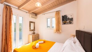 A bedroom with a bed, a dresser, an air conditioning unit, and a window with curtains. - Blue Villa 2 - With Private Pool (Mylopotamos)