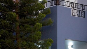 A two-story building with a stone wall in front, a large tree to the left, and a balcony with railings. - Blue Villa 2 - With Private Pool (Mylopotamos)