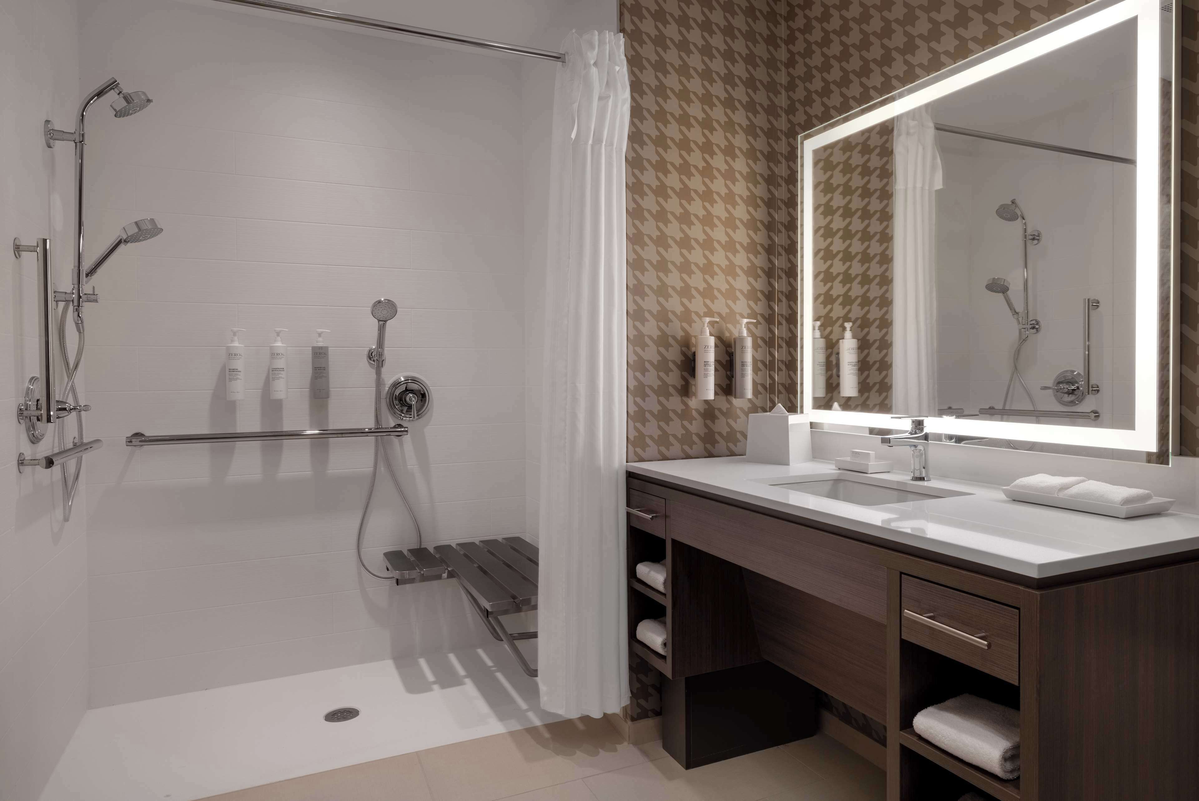 Un baño moderno con ducha, tocador y un espejo grande.