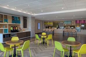 A modern restaurant with yellow chairs and tables, a counter with a menu, and a sign reading "Inspired Table". - Home2 Suites by Hilton Bristol (Bristol)