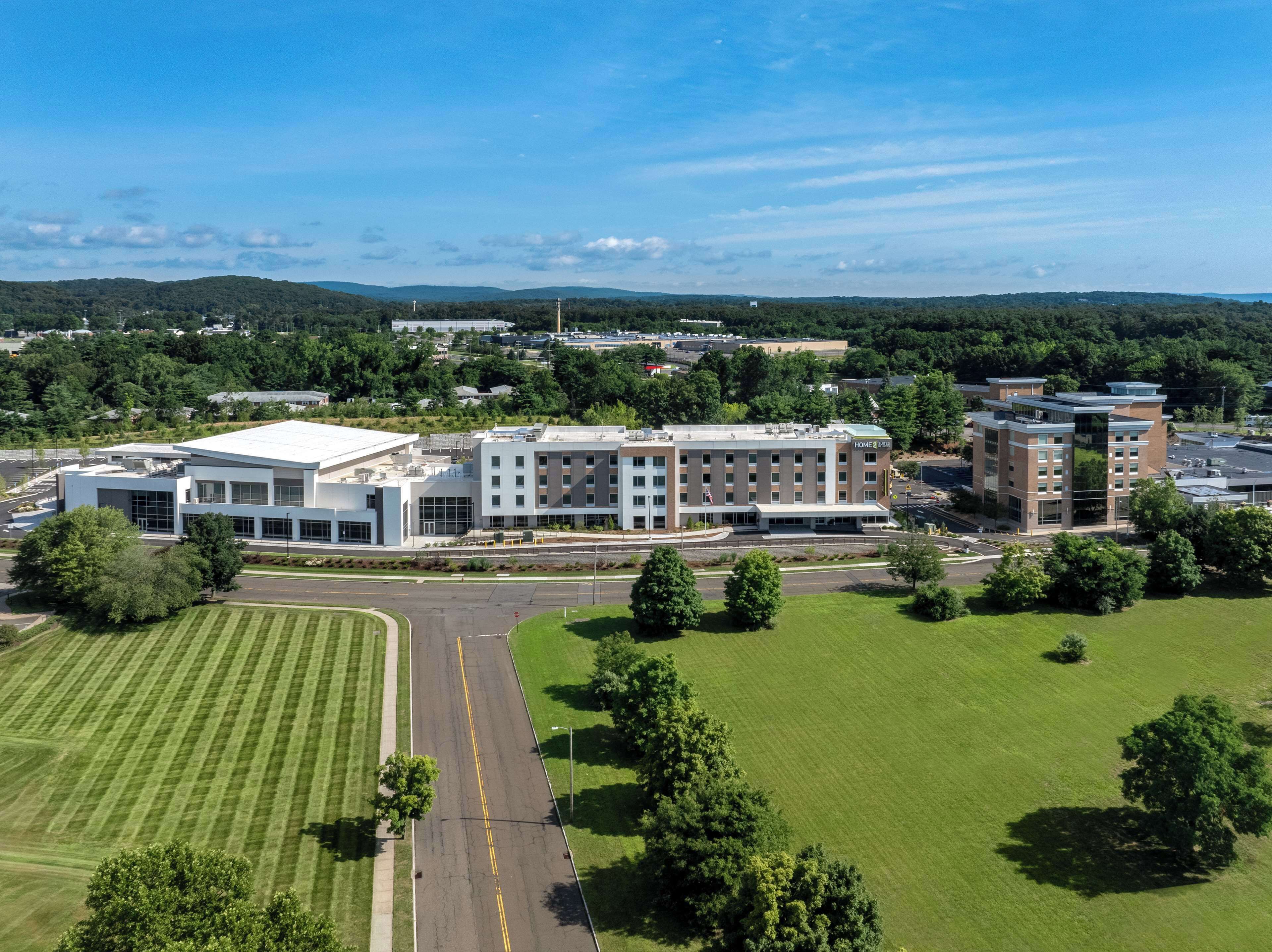 A modern hotel complex with multiple buildings, a central courtyard, and surrounding green spaces.