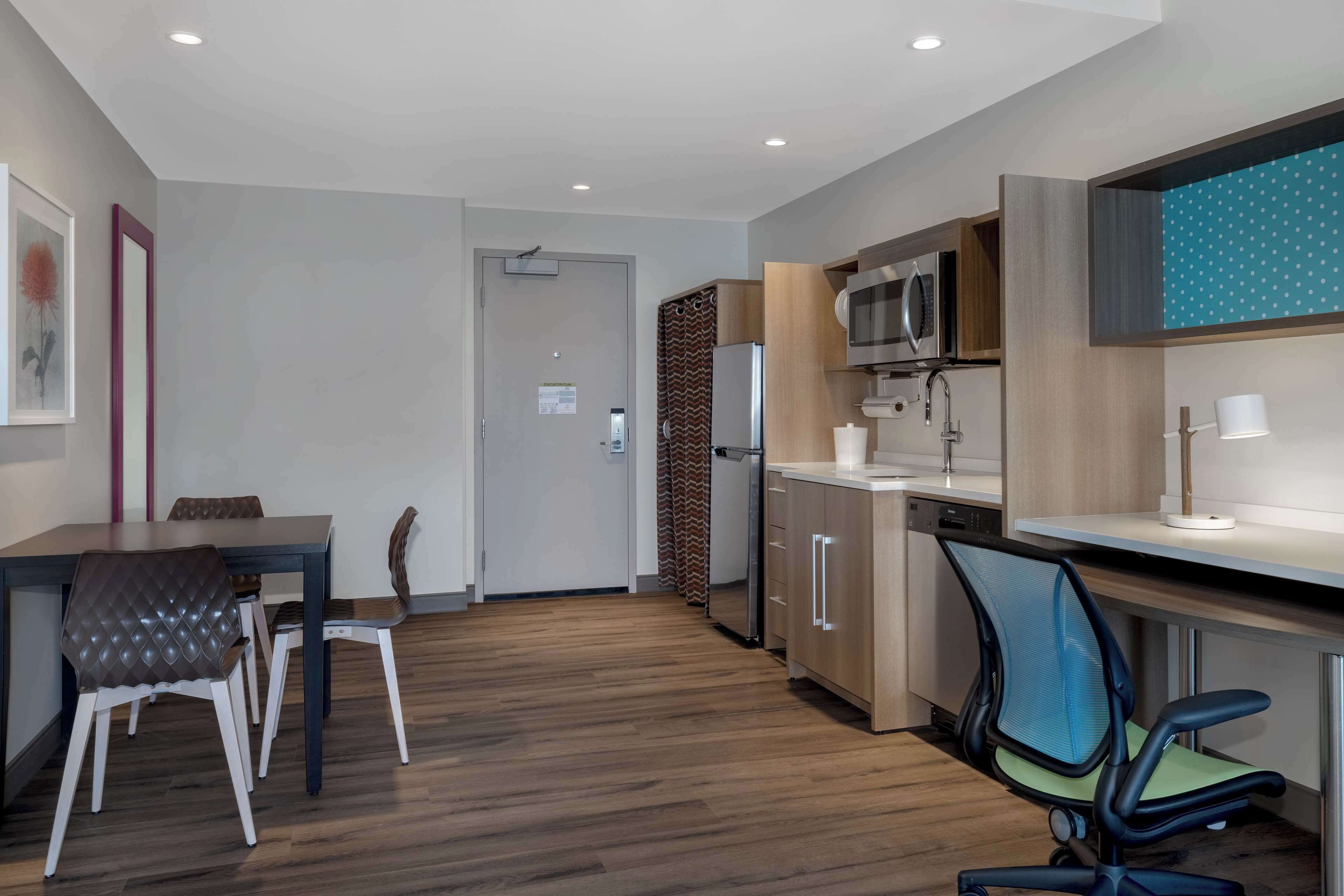 A modern kitchen with a microwave, refrigerator, and a dining area with a table and chairs.