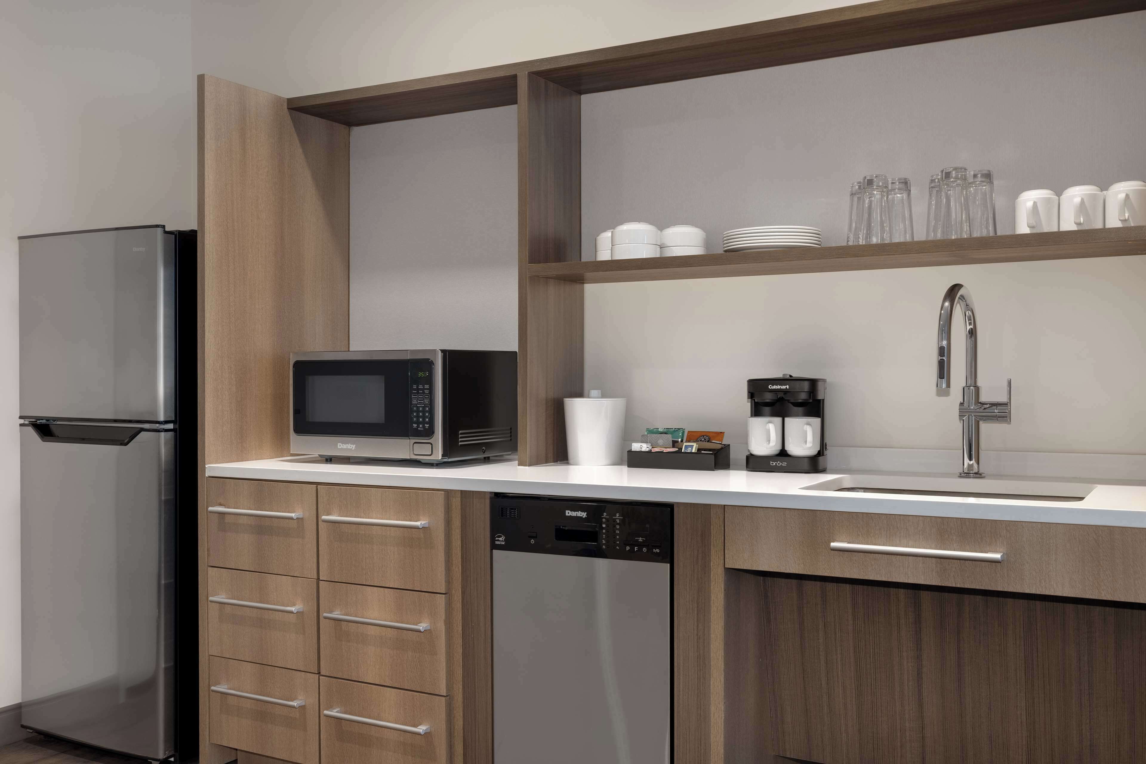 A modern kitchen with a stainless steel refrigerator, a microwave, a dishwasher, and a sink with a faucet.