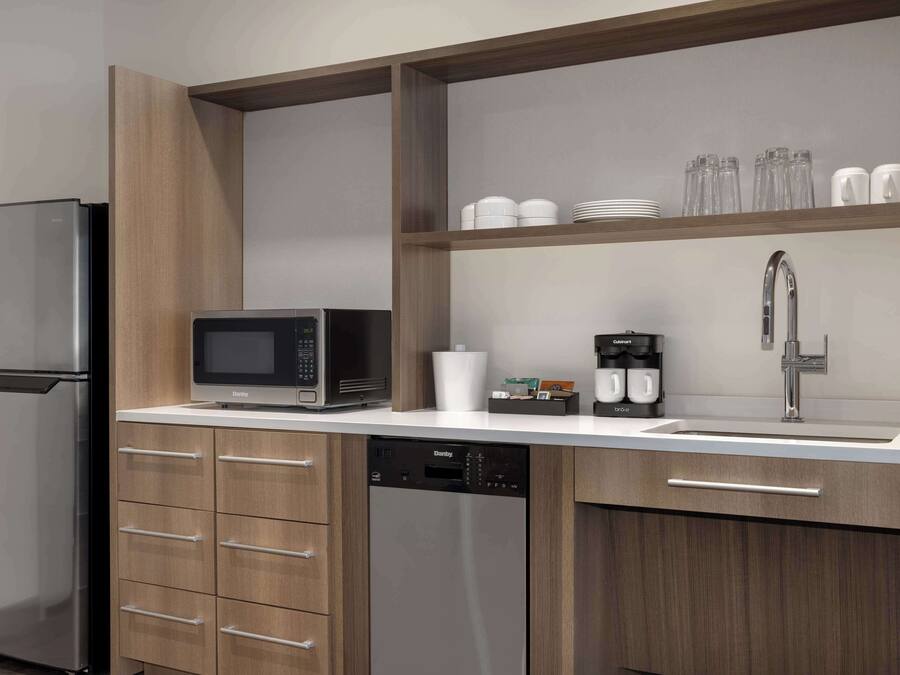 A modern kitchen with a stainless steel refrigerator, a microwave, a dishwasher, and a sink with a faucet.