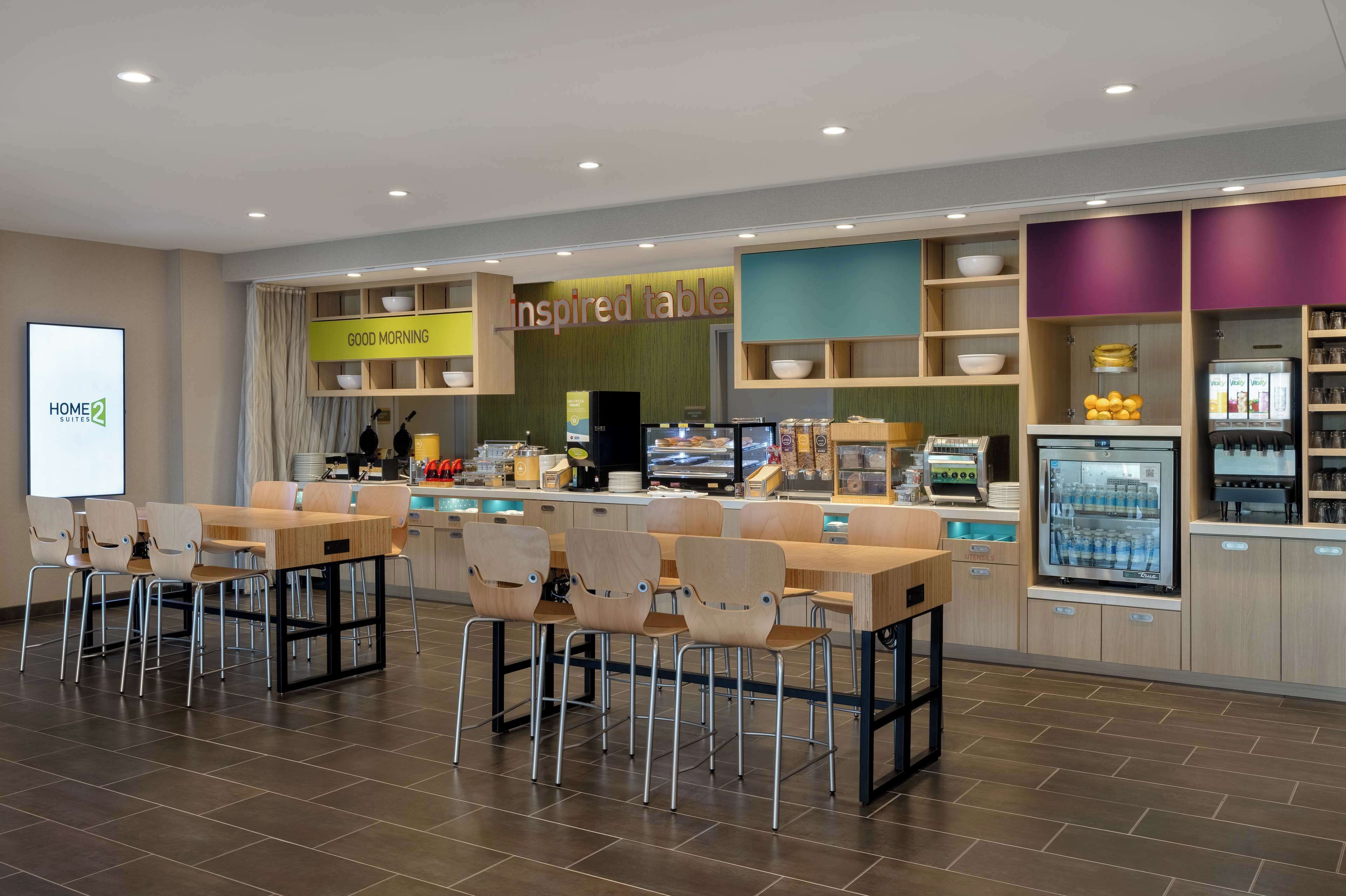 A modern restaurant with a 'Good Morning' sign, a 'Inspired Table' section, and a variety of seating options including tables and chairs.