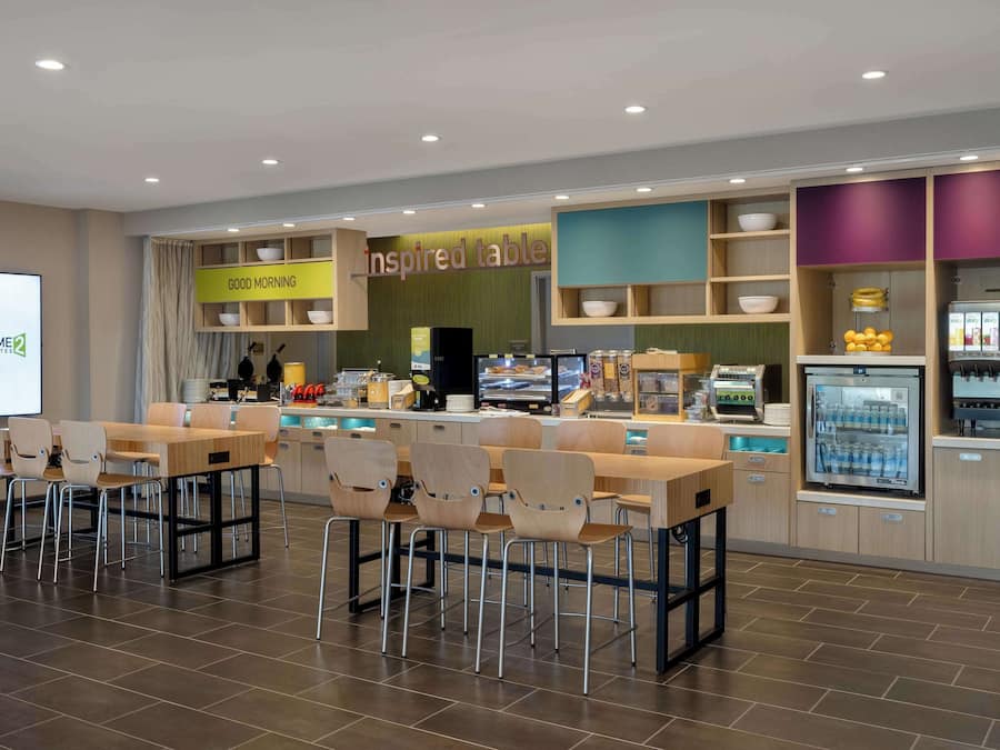 Ein modernes Restaurant mit einem 'Good Morning'-Schild, einem Bereich namens 'Inspired Table' und verschiedenen Sitzgelegenheiten, darunter Tische und Stühle.