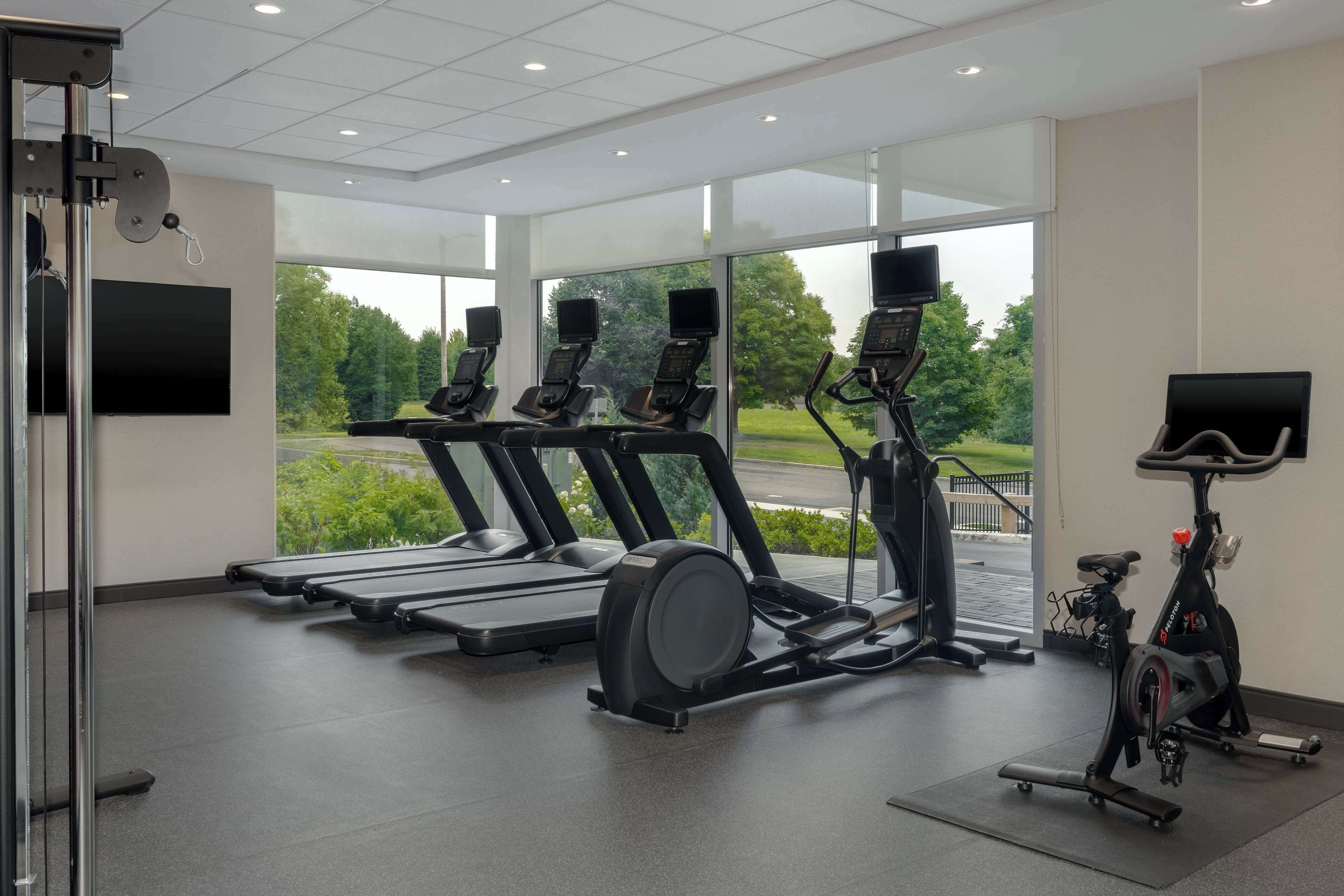 Et moderne fitnesscenter med løbebånd, spinningcykler og en romaskine.