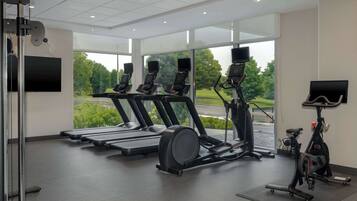 Et moderne fitnesscenter med løbebånd, spinningcykler og en romaskine.