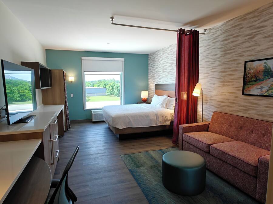 A modern hotel room with a bed, desk, and seating area.