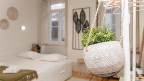 Ein Schlafzimmer mit einem Bett, einer hängenden Pflanze und einem Fenster.