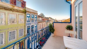 A balcony with a white bench, a potted plant, and a red car parked below. - Bonjardim City Flats - Relaxing Terrace (Porto)