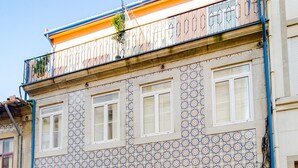 A two-story building with a patterned facade, blue doors, and a balcony with railings. - Bonjardim City Flats - Relaxing Terrace (Porto)