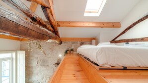A bedroom with a wooden bed, stone walls, and a skylight. - Bonjardim City Flats - Relaxing Terrace (Porto)