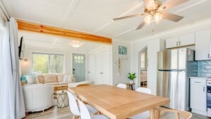 A spacious kitchen with a wooden dining table, white chairs, and modern appliances. - Beachy Palms Cottage on Lake Huron w/ Hot Tub! (Palms)