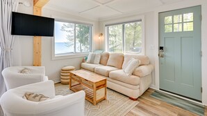 A cozy living room with a sofa, chairs, a coffee table, and a TV. - Beachy Palms Cottage on Lake Huron w/ Hot Tub! (Palms)
