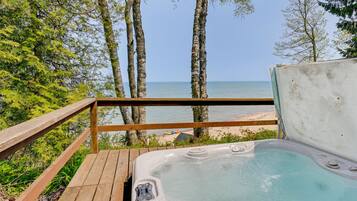 Un bain à remous sur une terrasse en bois, avec vue sur la plage et l’océan.