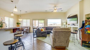 A spacious living area with a kitchen, bar stools, a sofa, a recliner, and a TV. - Mesquite Vacation Rental - Close to Golf Courses! (Mesquite)
