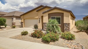 A residential house with a garage, a driveway, and landscaped garden with small shrubs and a palm tree. - Mesquite Vacation Rental - Close to Golf Courses! (Mesquite)