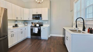 A modern kitchen with white cabinets, a stainless steel refrigerator, a built-in oven, and a black faucet. - NEW! Classy 3BR Home ~ 5 min to DT + Eateries (Knoxville)