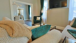 A living room with a sofa, a coffee table, and a television mounted on the wall. - NEW! Classy 3BR Home ~ 5 min to DT + Eateries (Knoxville)