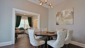 A dining area with a round table and six upholstered chairs, a chandelier, and a painting on the wall. - NEW! Classy 3BR Home ~ 5 min to DT + Eateries (Knoxville)