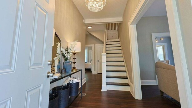 A hallway with a staircase, a chandelier, and a console table with decorative items. - NEW! Classy 3BR Home ~ 5 min to DT + Eateries (Knoxville)