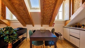Une cuisine moderne avec un plafond en bois, des fenêtres de toit, une table à manger avec des chaises et un banc intégré agrémenté d’une plante.