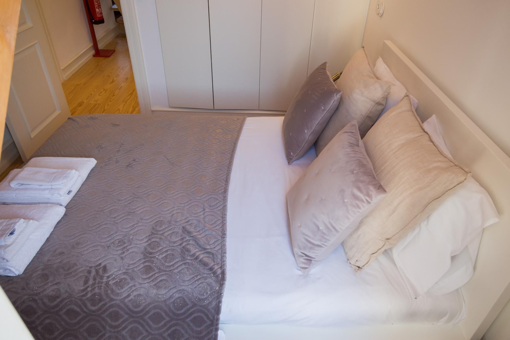 Un lit bien fait, avec une couvre-lit à motifs, plusieurs oreillers et des serviettes pliées posées sur le côté.