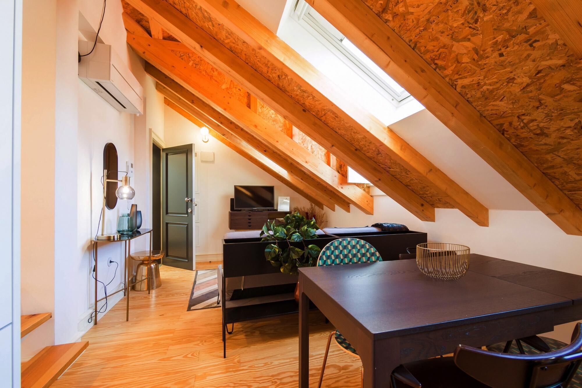 Une pièce mansardée chaleureuse avec un plafond en bois, une table à manger et un téléviseur.