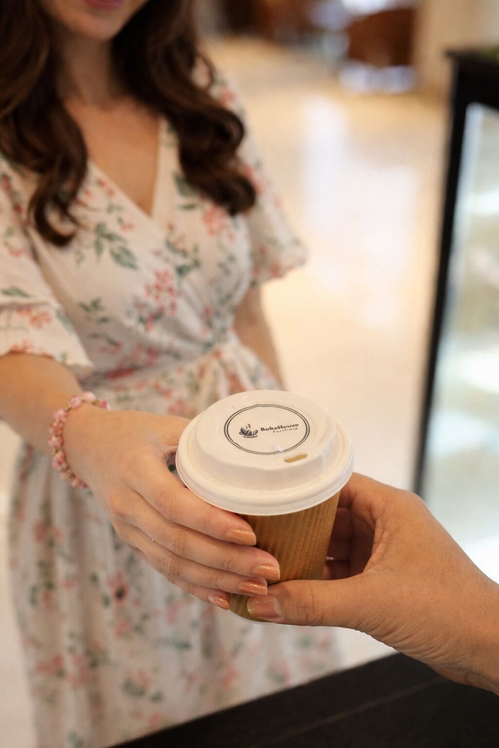 A person holding a coffee cup with a lid, and another person reaching out to take it.