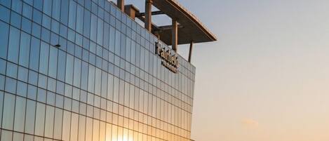 Un edificio moderno con fachada de vidrio y un cartel que dice 'Hotel'.